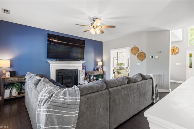 living room featuring visible vents, dark wood-type flooring, ceiling fan, and a fireplace