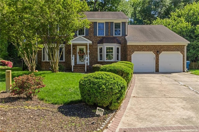 colonial inspired home featuring roof with shingles, a front yard, a garage, brick siding, and concrete driveway
