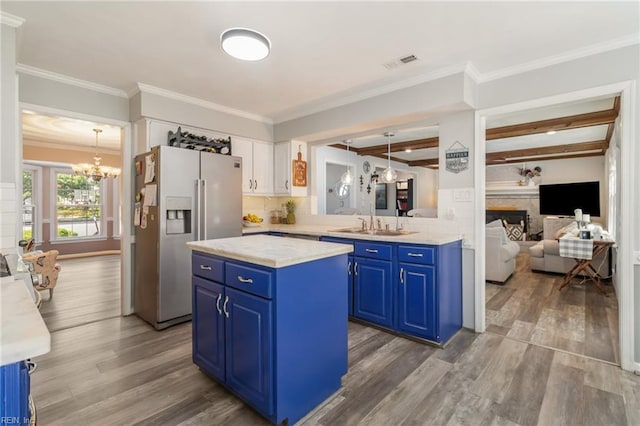 kitchen featuring blue cabinets, visible vents, wood finished floors, stainless steel fridge with ice dispenser, and a notable chandelier