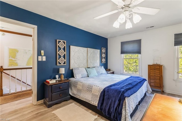 bedroom featuring visible vents, baseboards, wood finished floors, and multiple windows