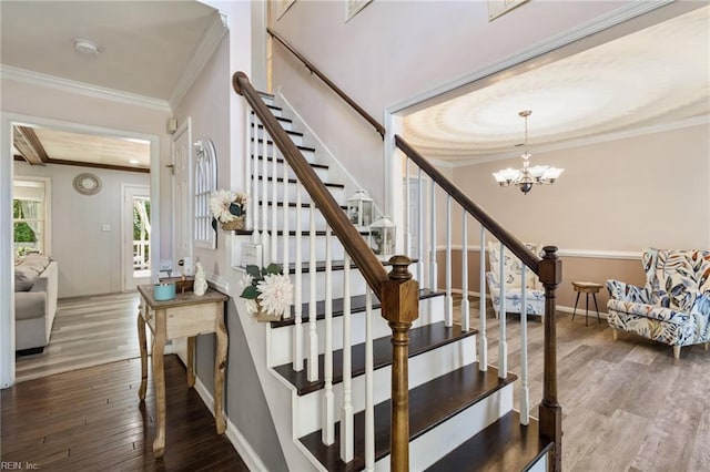 stairway featuring crown molding, baseboards, a notable chandelier, and hardwood / wood-style floors