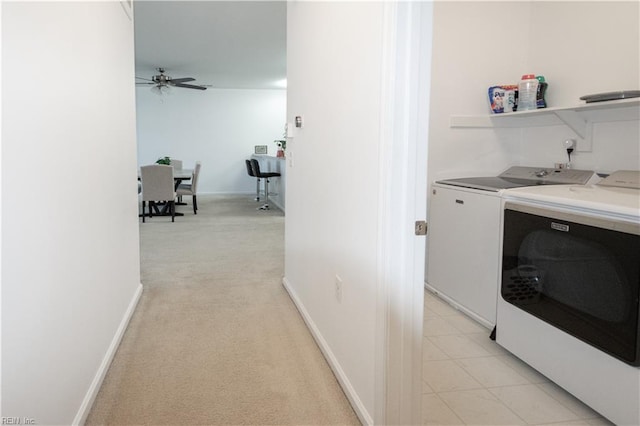 clothes washing area featuring independent washer and dryer, laundry area, light colored carpet, a ceiling fan, and baseboards