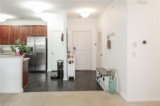 kitchen featuring brown cabinetry, light countertops, baseboards, and stainless steel fridge with ice dispenser