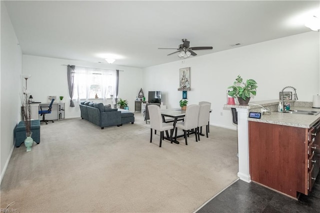carpeted dining area with a ceiling fan, baseboards, and a sink