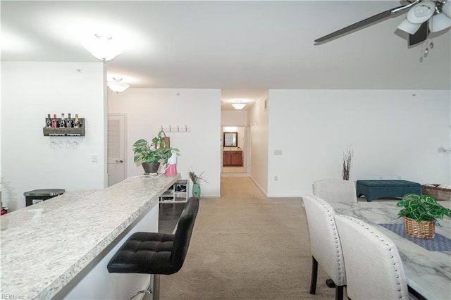 interior space featuring baseboards, ceiling fan, and light colored carpet