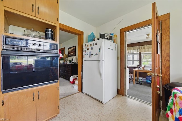 kitchen featuring freestanding refrigerator, light floors, and oven