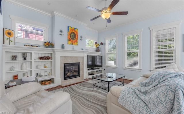 living room featuring a high end fireplace, a ceiling fan, a wealth of natural light, and ornamental molding