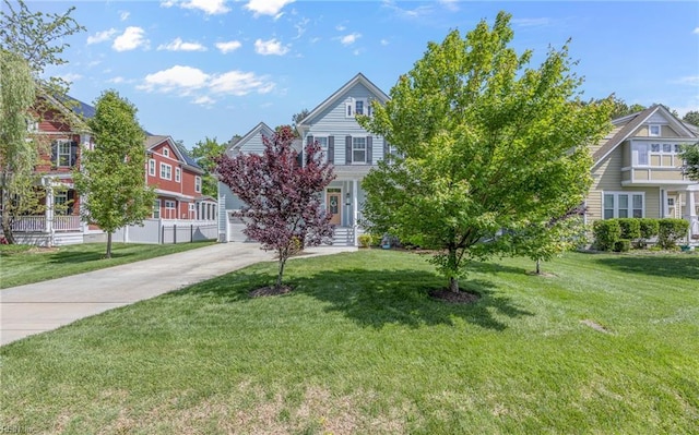 view of front facade featuring concrete driveway, fence, a residential view, and a front yard