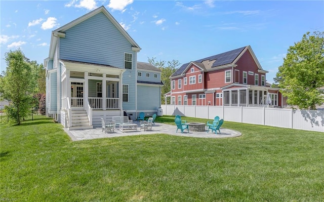 rear view of property with fence, an outdoor fire pit, a sunroom, a patio area, and a lawn