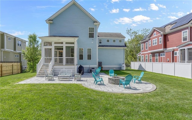 back of property with a yard, a patio, a sunroom, and an outdoor fire pit