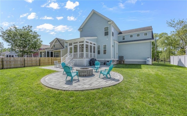 back of property with an outdoor fire pit, a sunroom, a fenced backyard, a patio area, and a yard