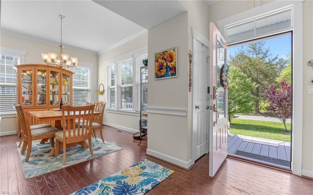 dining space with crown molding, wood-type flooring, baseboards, and a notable chandelier