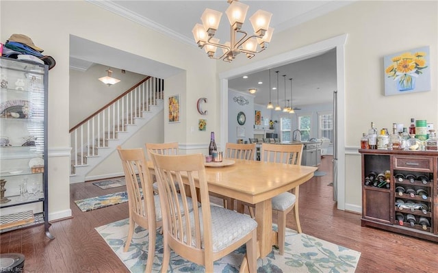 dining room with wood finished floors, stairway, baseboards, an inviting chandelier, and ornamental molding