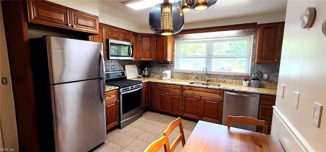 kitchen with light tile patterned flooring, light stone countertops, tasteful backsplash, a sink, and stainless steel appliances