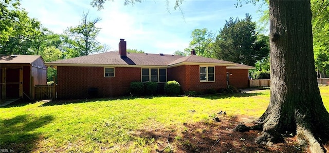 back of property with brick siding, a yard, and a chimney