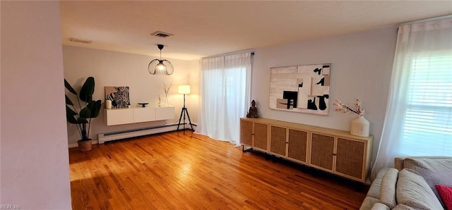 interior space featuring visible vents, a baseboard radiator, wood finished floors, and multiple windows