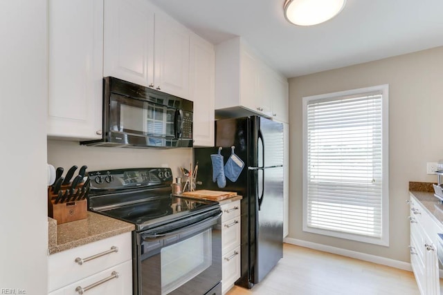 kitchen featuring plenty of natural light, white cabinetry, baseboards, and black appliances