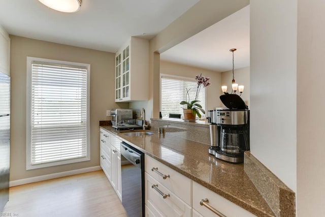 kitchen with dishwasher, a sink, white cabinets, glass insert cabinets, and light wood-style flooring