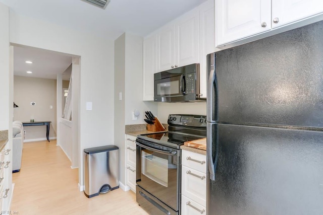 kitchen featuring light wood-type flooring, light countertops, baseboards, white cabinets, and black appliances