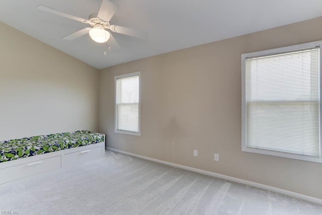 unfurnished bedroom featuring baseboards, light carpet, ceiling fan, and lofted ceiling