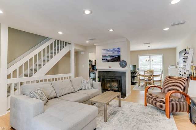 living room featuring recessed lighting, visible vents, light wood finished floors, and stairway