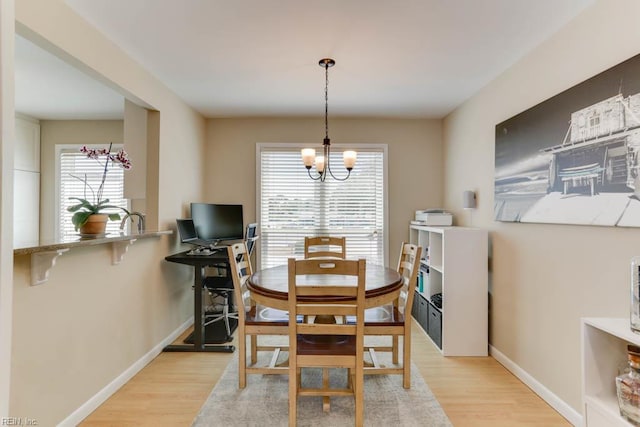 dining space featuring light wood-style floors, a notable chandelier, and a healthy amount of sunlight