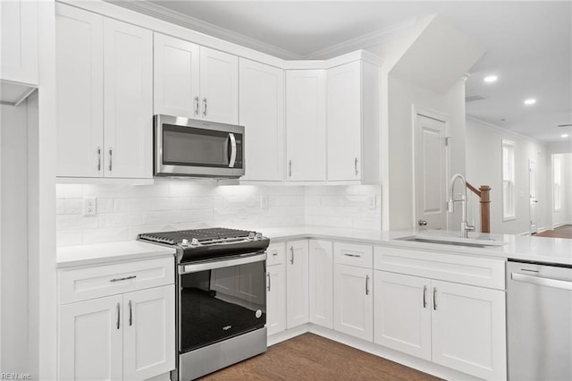 kitchen with crown molding, light countertops, white cabinetry, a sink, and stainless steel appliances