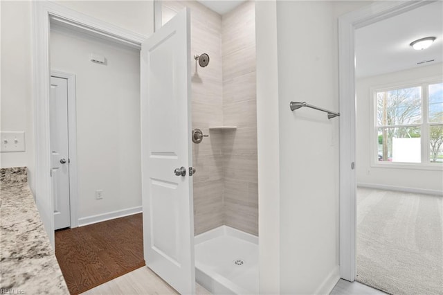 full bathroom with baseboards, a tile shower, and wood finished floors