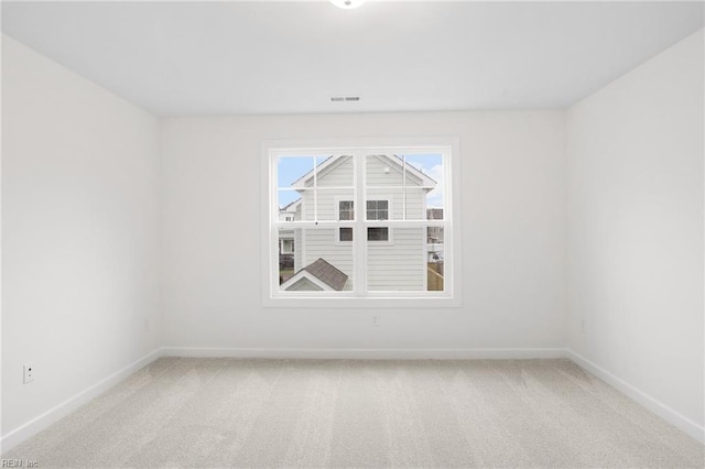 unfurnished room featuring baseboards, light carpet, and visible vents