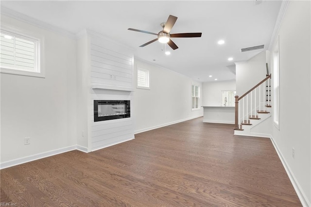 unfurnished living room with dark wood-style flooring, a fireplace, a ceiling fan, visible vents, and ornamental molding