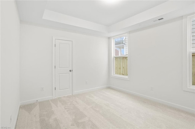unfurnished room with visible vents, a raised ceiling, baseboards, and carpet floors