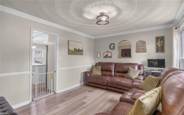 living area featuring baseboards, ornamental molding, and wood finished floors