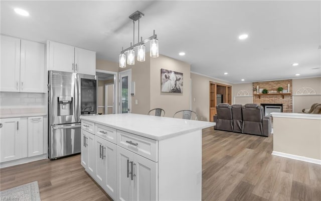 kitchen with a kitchen island, light wood-style floors, light countertops, white cabinetry, and stainless steel fridge with ice dispenser