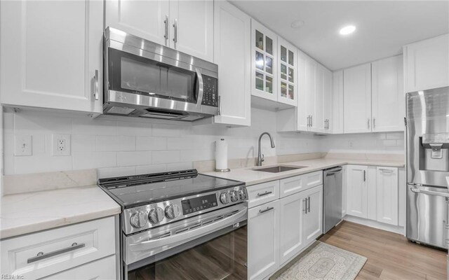 kitchen with white cabinetry, appliances with stainless steel finishes, glass insert cabinets, and a sink