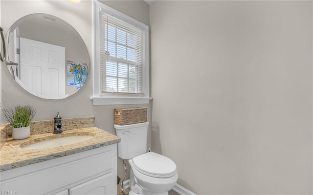 bathroom with toilet, baseboards, and vanity