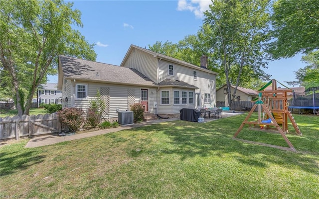 rear view of house with a patio, a fenced backyard, a chimney, a playground, and a yard