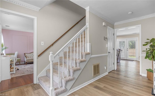 staircase featuring visible vents, ornamental molding, baseboards, and wood finished floors