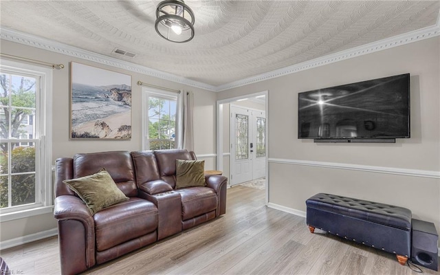 living room featuring crown molding, baseboards, visible vents, and wood finished floors