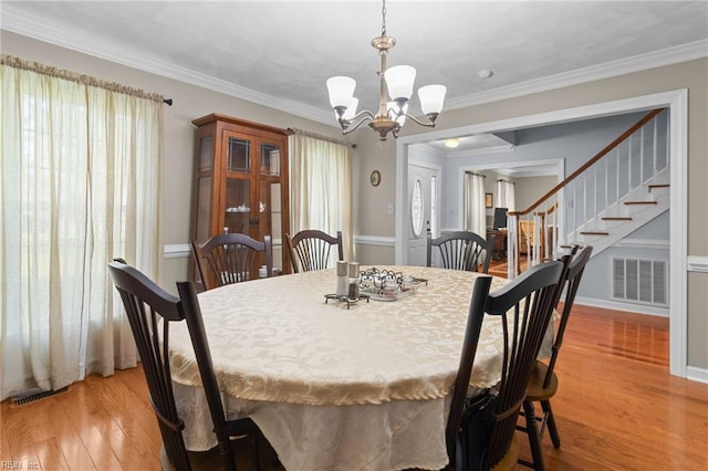 dining room with visible vents, a wealth of natural light, stairway, light wood-style flooring, and a notable chandelier