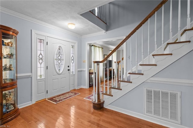 entrance foyer with visible vents, ornamental molding, hardwood / wood-style floors, baseboards, and stairway