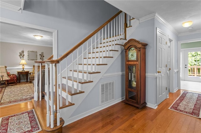 staircase with visible vents, ornamental molding, and wood finished floors