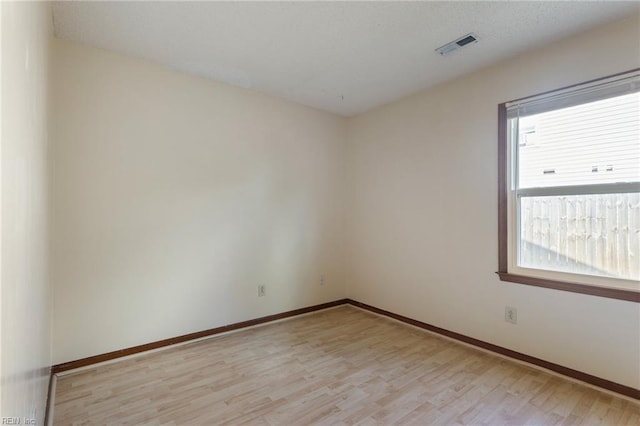 unfurnished room with baseboards, visible vents, plenty of natural light, and light wood-type flooring