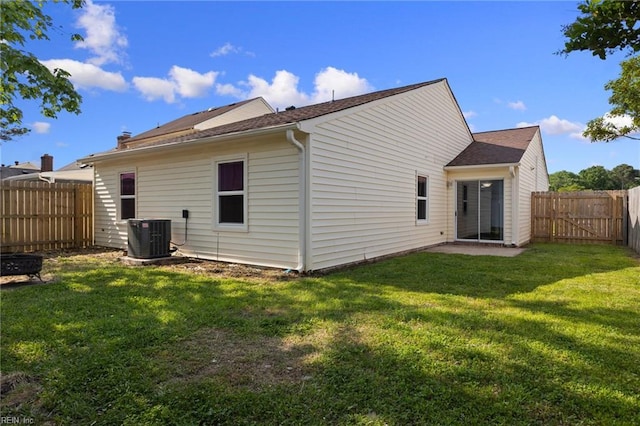 back of house featuring central AC unit, a fenced backyard, a yard, and a shingled roof