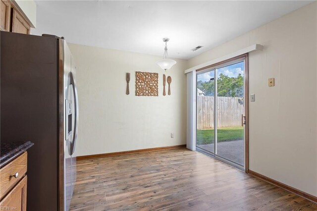 unfurnished dining area featuring baseboards, wood finished floors, and visible vents