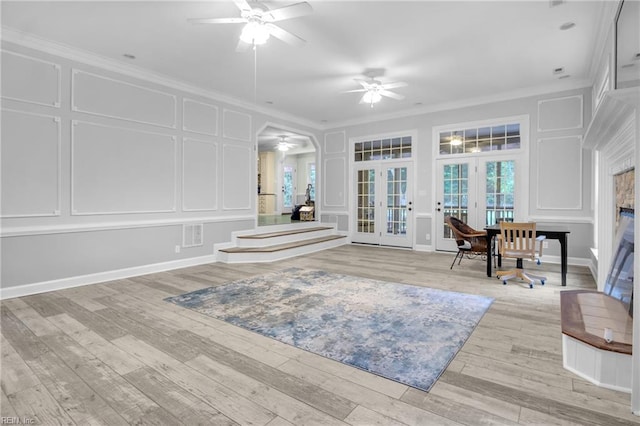 interior space with french doors, crown molding, ceiling fan, and a decorative wall