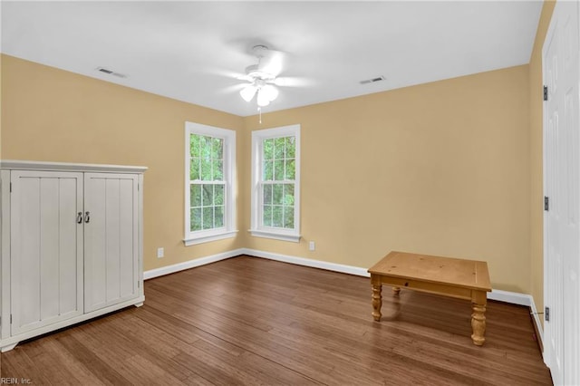 empty room featuring visible vents, a ceiling fan, baseboards, and wood finished floors