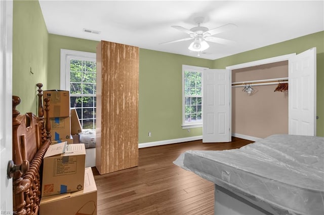 bedroom featuring baseboards, visible vents, multiple windows, and wood finished floors