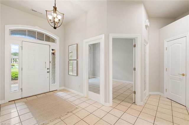 foyer entrance with visible vents, baseboards, light tile patterned floors, and an inviting chandelier