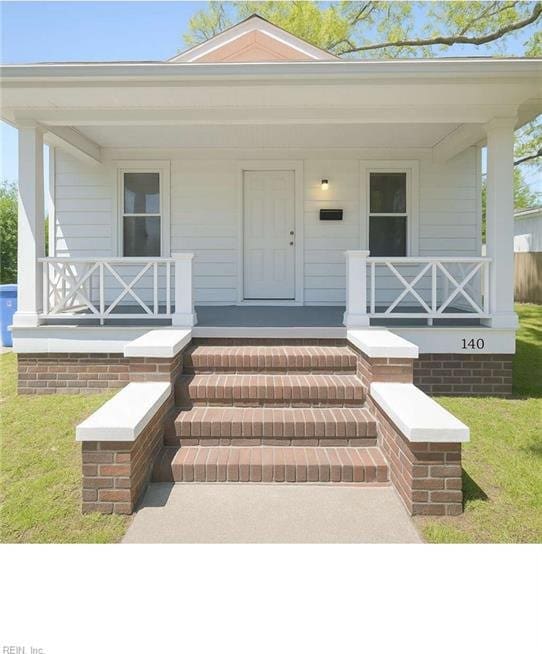 entrance to property with a porch and a yard