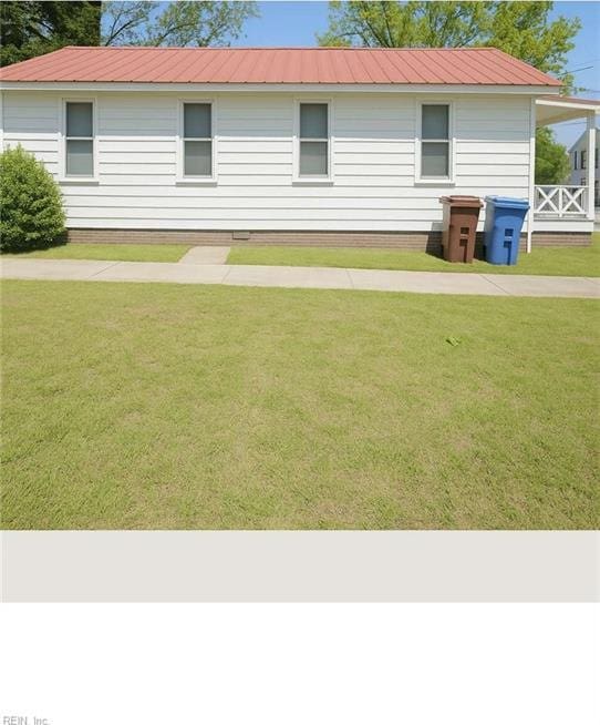 rear view of property featuring a yard and metal roof